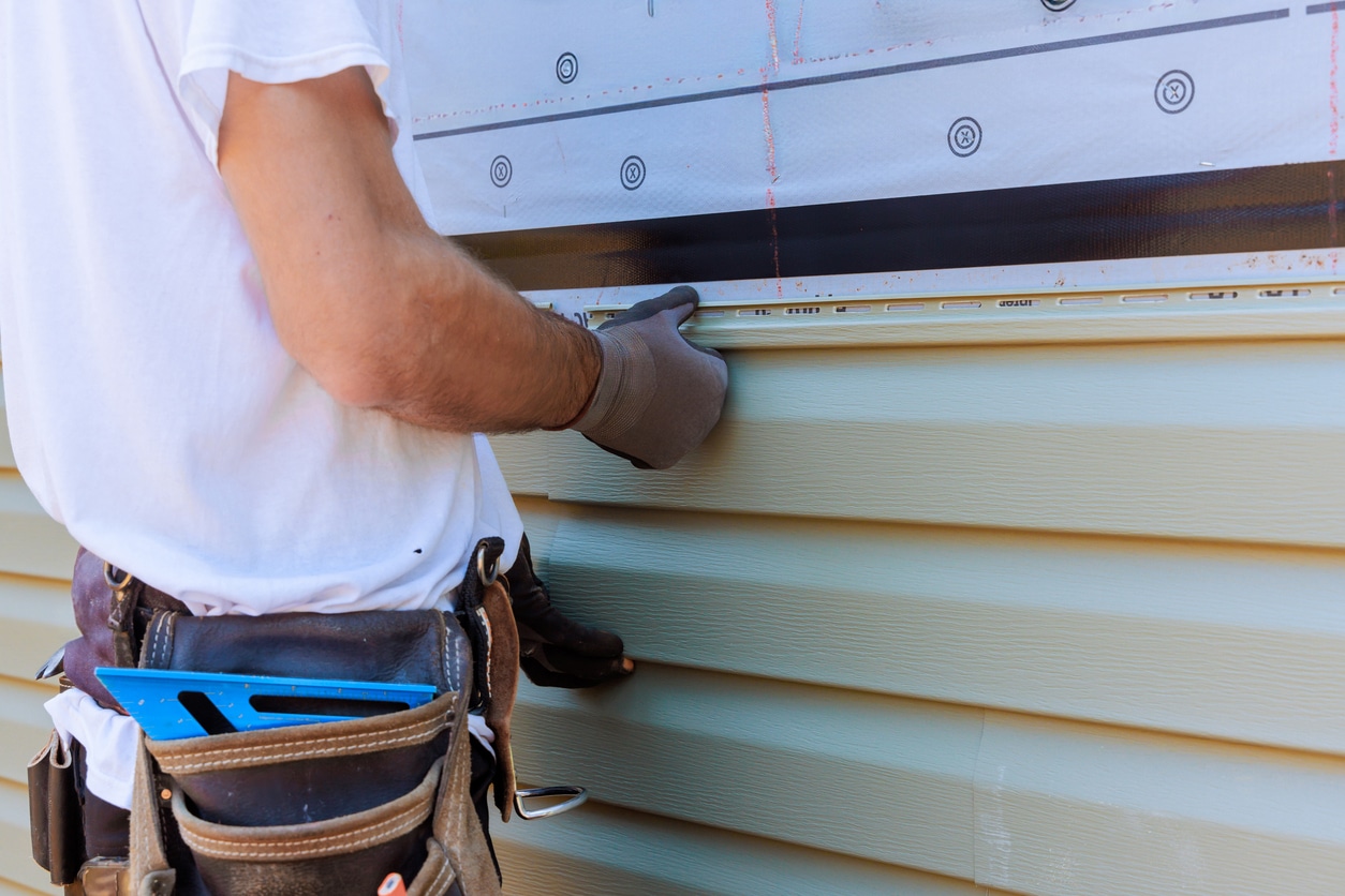 Person installing vinyl PVC siding during construction
