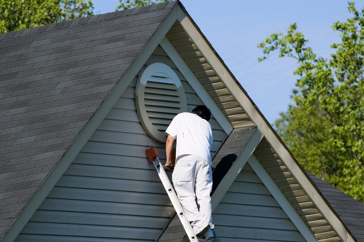 Painter working at top of extension ladder