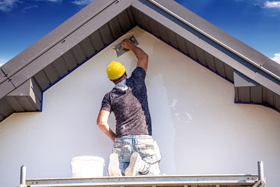 Worker applying stucco to exterior of home